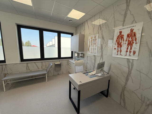 Gabinet ortopedyczny z kozetką i planszami anatomicznymi mięśni