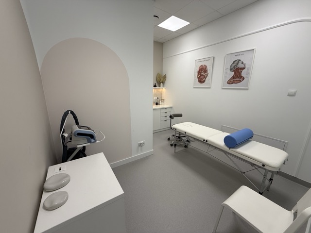 Gabinet fizjoterapii z kozetką do masażu i aparatem do fali uderzeniowej